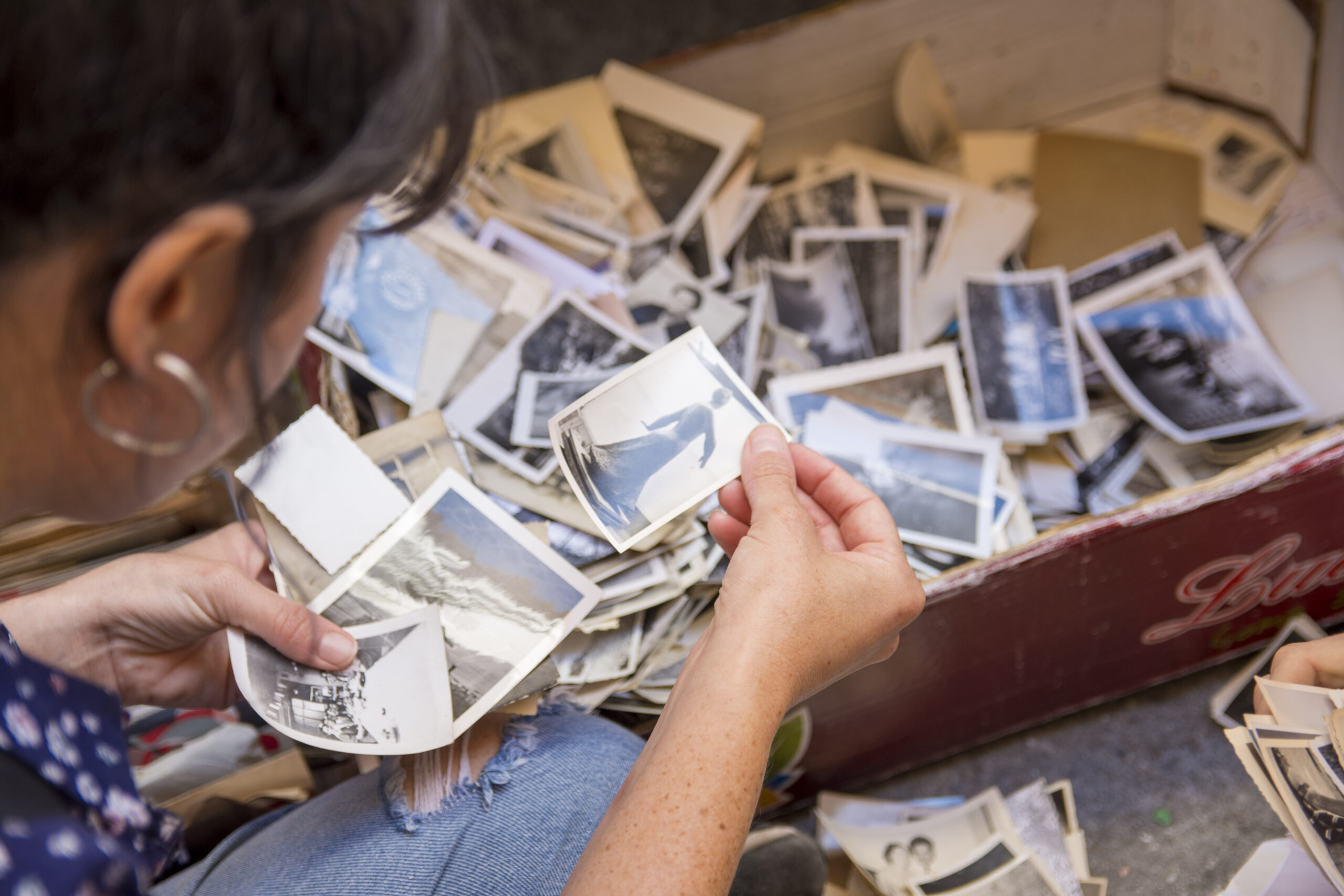 Southern Oregon Photo Manager looking through box of unorganized photographs.