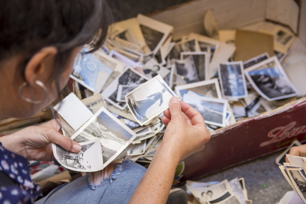A woman sorts through a box of old photographs, trying to determine who the subjects are and if they are meaningful to future generations.