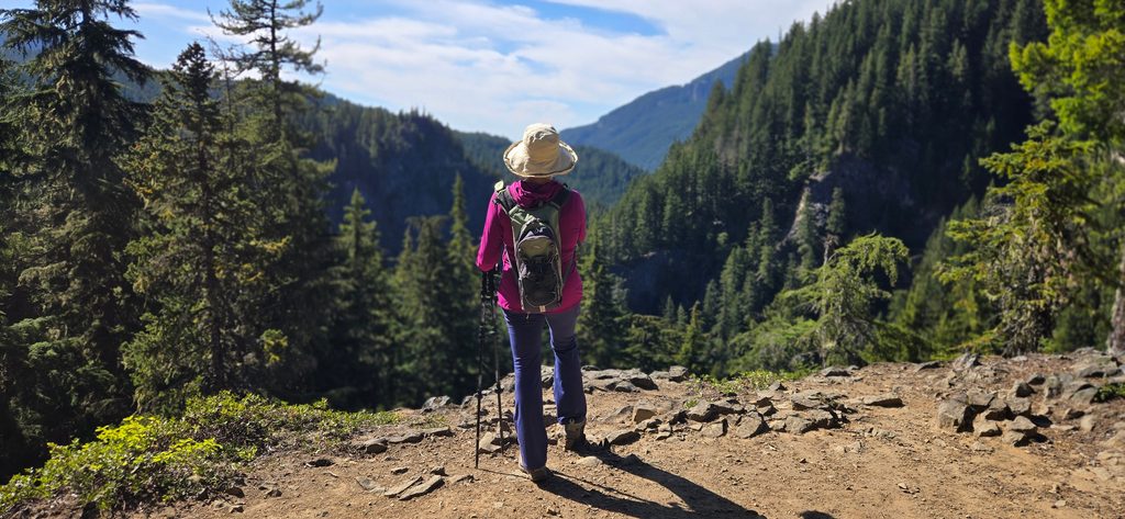 A Southern Oregon photo manager views forested mountains from a hiking trail.